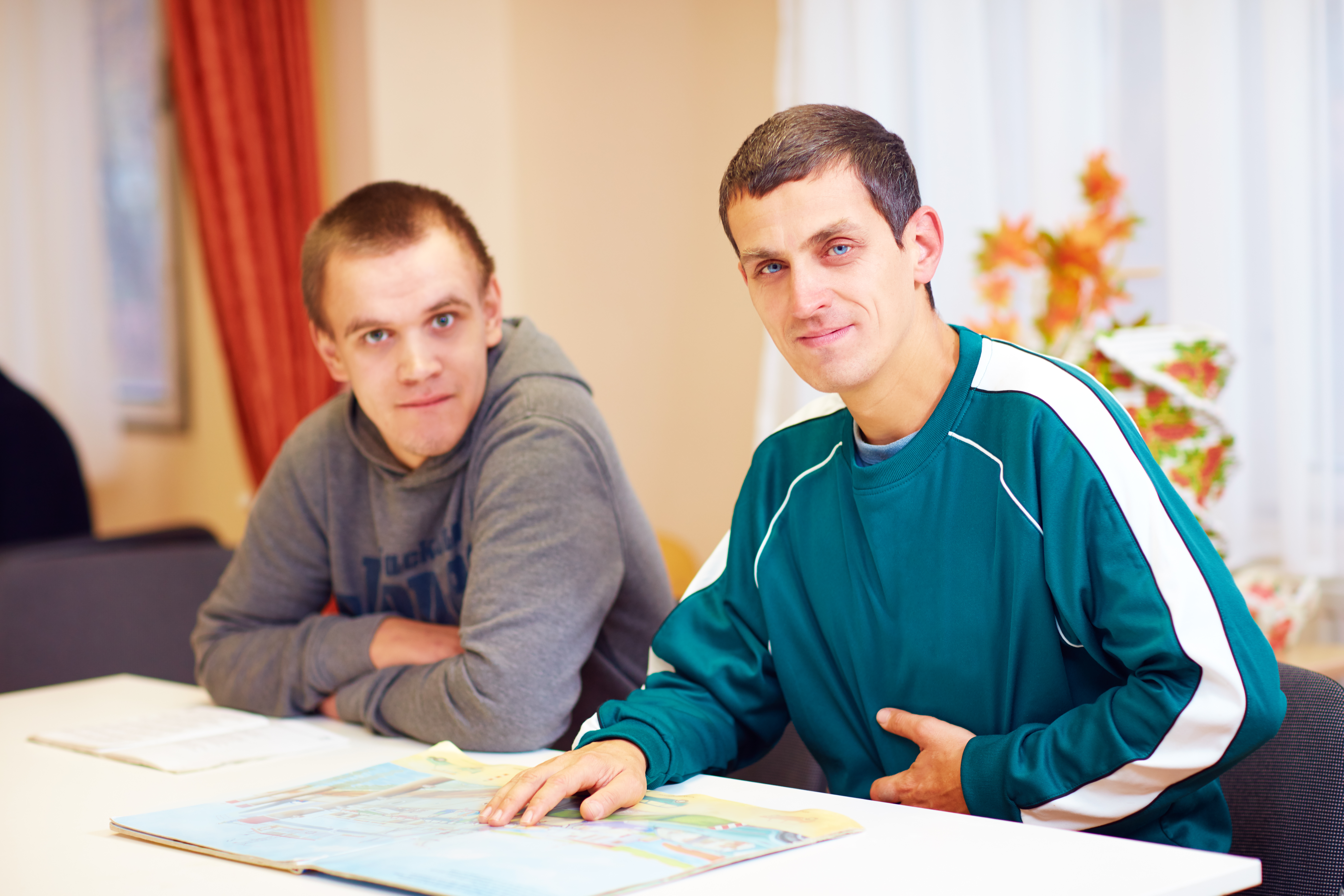 Cheerful adult men sitting at a desk going over paperwork looking directly at camera