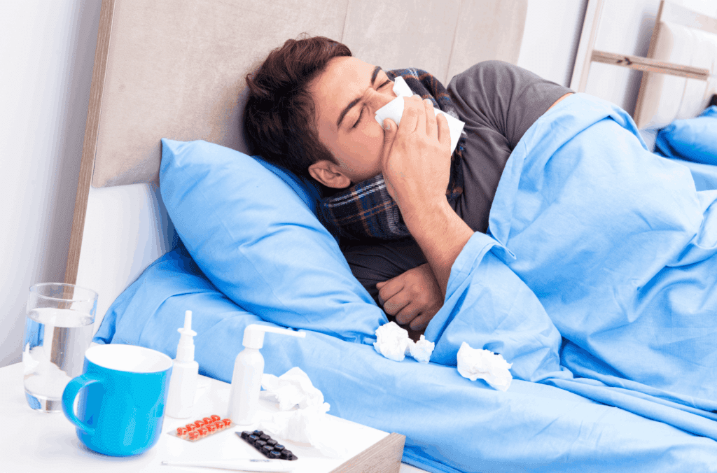 A man ill in bed with tissues and medicines